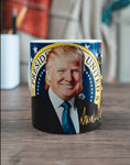 Donald Trump Signature Coffee Mug - Trump's smiling face adorns the front of this Presidential coffee mug along with his famous signature in gold.  Make America Great Again is on the other side with the White House pictured.