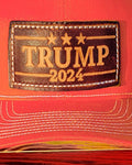 Trucker-Style Trump 2024 Leather Patch Hat with white mesh back.  The leather patch is custom made, hand-cut, and hand-stamped in the USA. Available in Orange. 