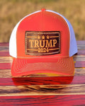 Orange Trucker-Style Trump 2024 Leather Patch Hat with white mesh back.  The leather patch is custom made, hand-cut, and hand-stamped in the USA. Available in Orange + 2 other colors 